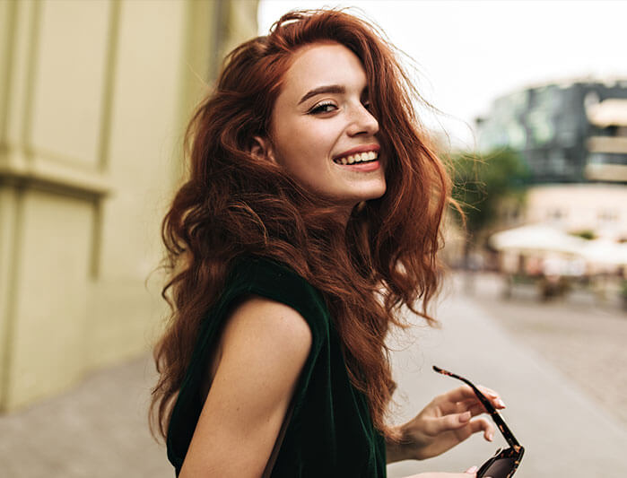 Woman walking down the sidewalk, smiling back at the camera